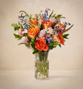 Bouquet of colorful flowers in a clear vase on a beige background