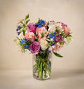 Bouquet of colorful flowers in a clear vase on a beige background