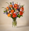 Bouquet of colorful flowers in a clear vase on a neutral background