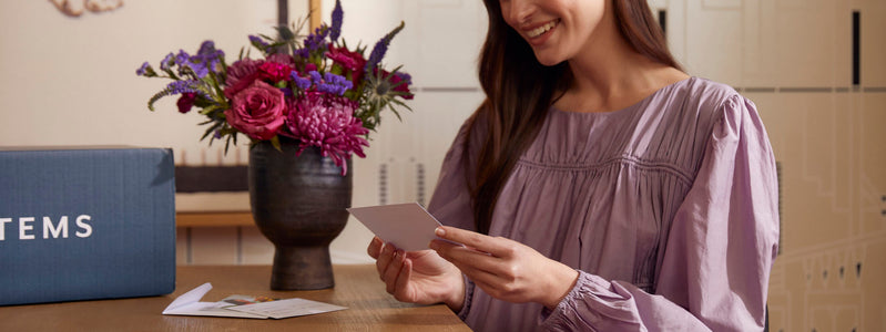 Woman reading notes attached to UrbanStems flower delivery