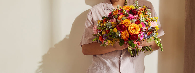 Person holding rainbow flower bouquet