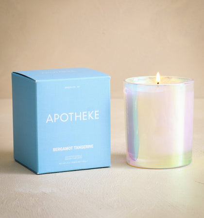 Iridescent candle next to a blue box labeled 'Apotheke' on a beige background