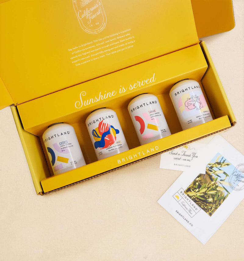 Open yellow box containing four Brightleaf tea cans with a card on a beige background