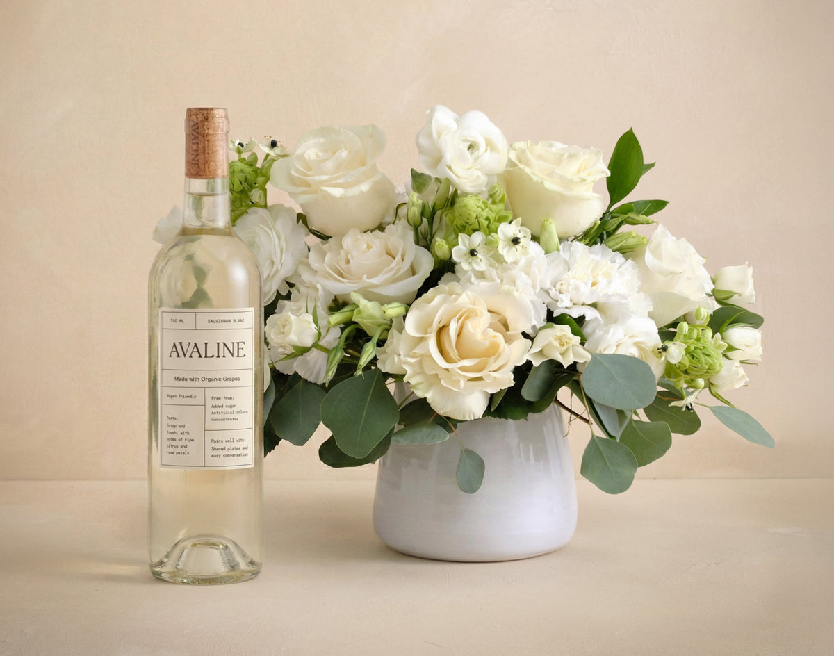 Bottle of Avaline wine with a bouquet of white flowers on a beige background