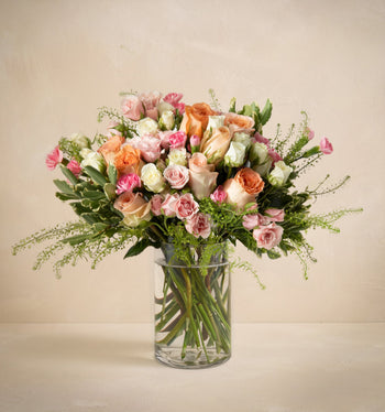 Bouquet of flowers in a clear vase on a beige background