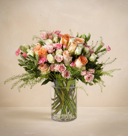 Bouquet of flowers in a clear vase on a beige background