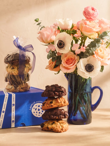 Cookies, a bouquet of flowers, and a box on a wooden surface.