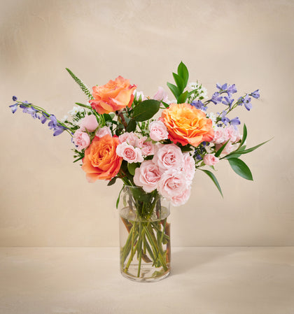 Bouquet of flowers in a clear vase on a beige background