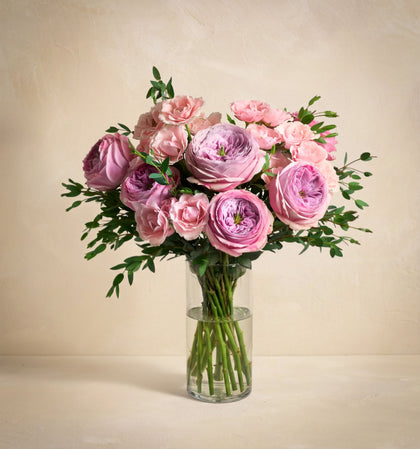 Bouquet of pink roses in a clear vase on a beige background