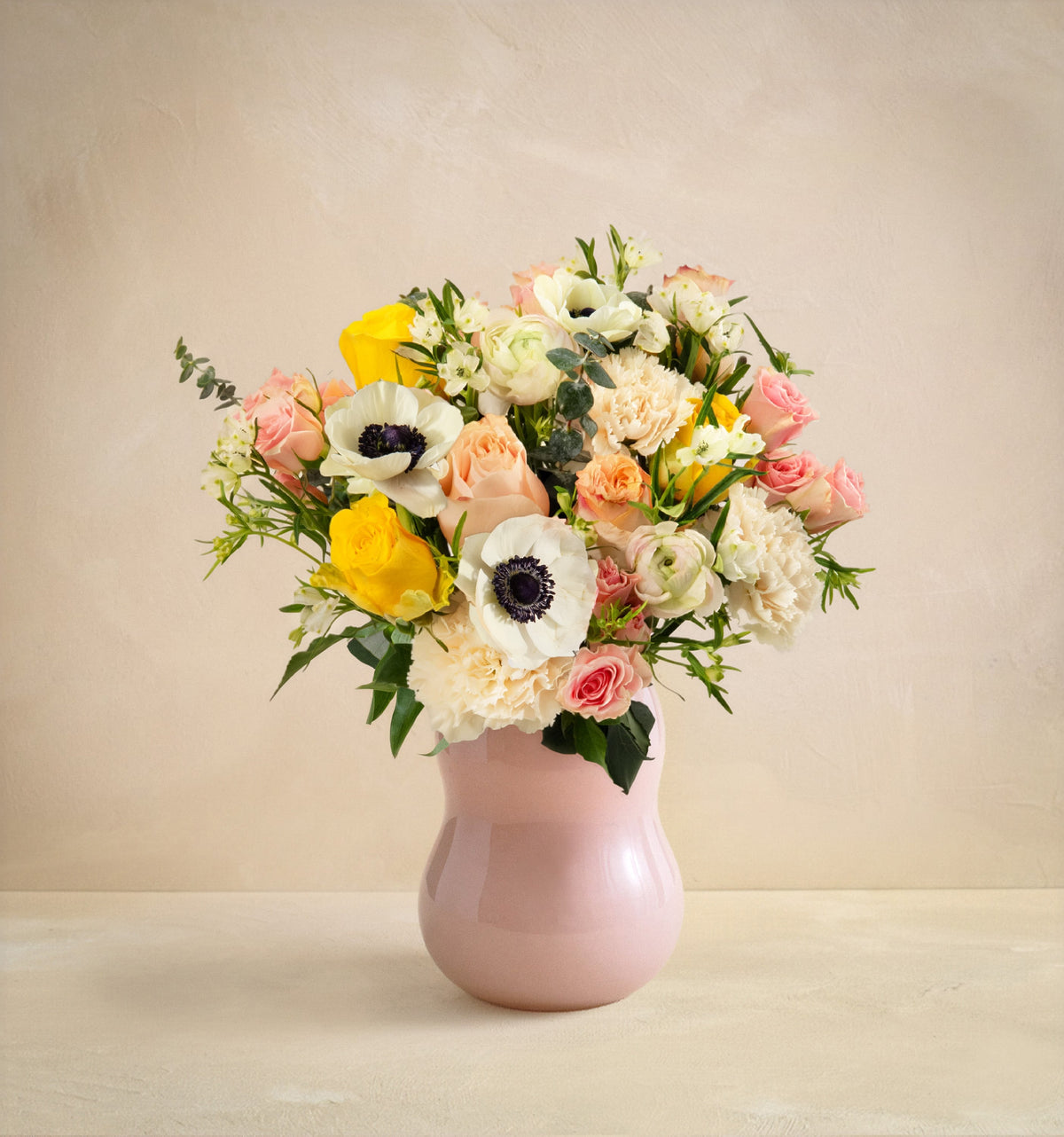 Bouquet of flowers in a pink vase on a beige background