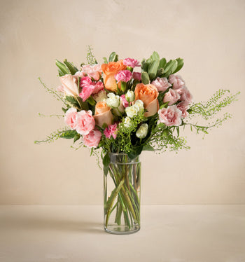 Bouquet of flowers in a clear vase on a beige background