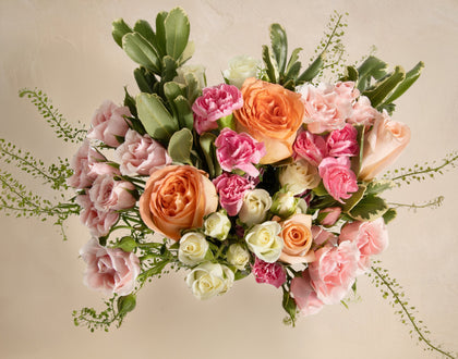 Bouquet of colorful flowers including roses and hydrangeas on a beige background